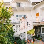 the couple walks down the white spiral stairs together
