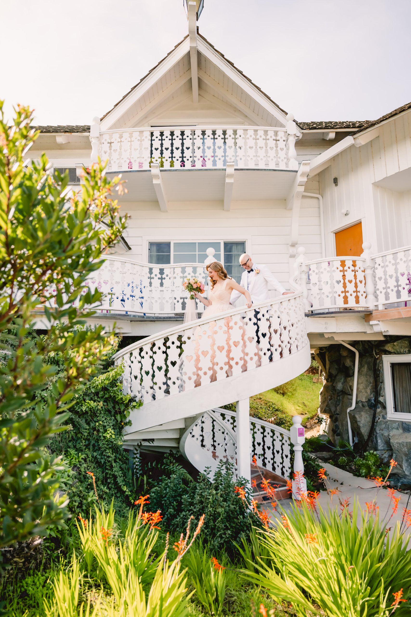 the couple walks down the white spiral stairs together