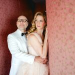couple cuddles up against quirky pink wallpaper