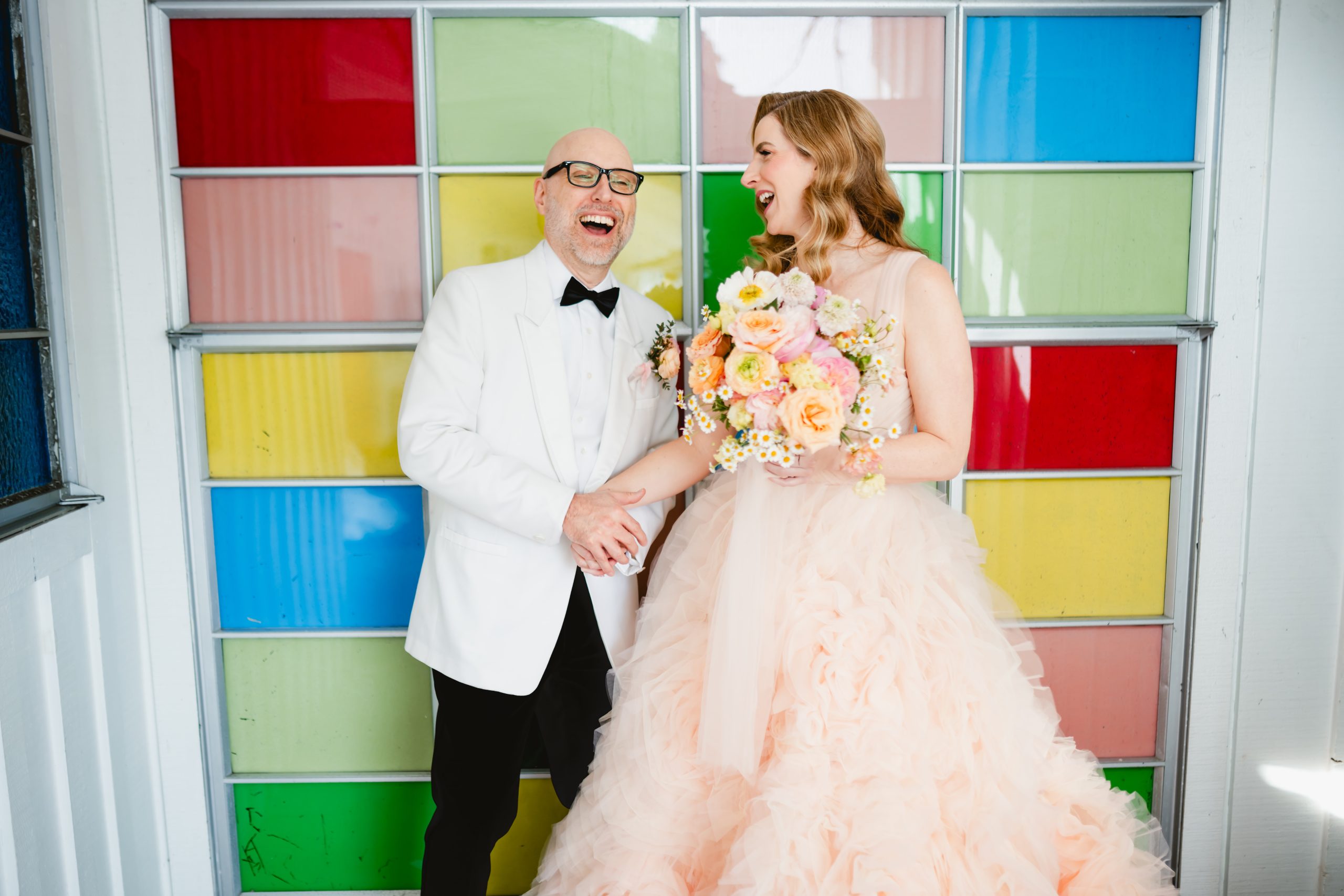 a couple dances around in front of a colorful glass wall at Madonna Inn