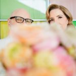 the couple peeks out from behind the bride's bouquet