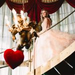 a bride in a fluffy pink wedding gown walks down the stairs into the ceremony