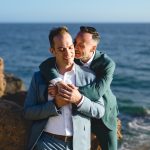 two grooms embrace on the beach in malibu