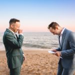 two grooms laugh hysterically during their elopement ceremony as the sun sets over the ocean in Malibu