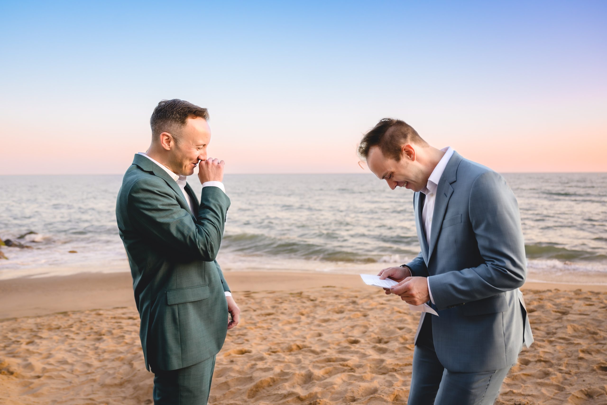 two grooms laugh hysterically during their elopement ceremony as the sun sets over the ocean in Malibu