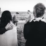 a touching moment as the couple reads their vows with their guests holding onto each other in the foreground