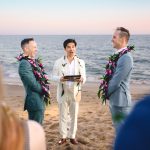 two grooms get married on a beach in malibu, surrounded by friends and family