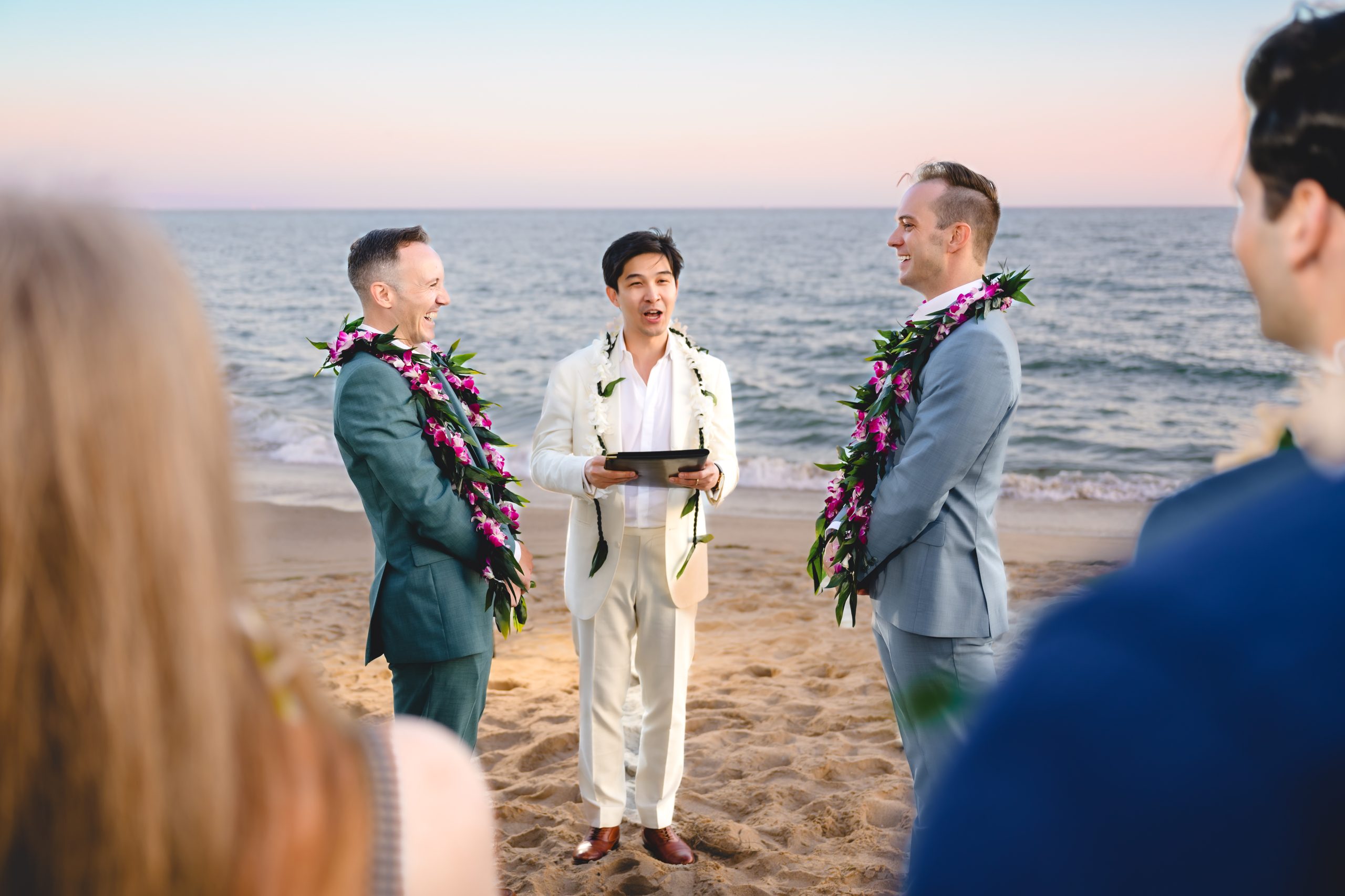 two grooms get married on a beach in malibu, surrounded by friends and family