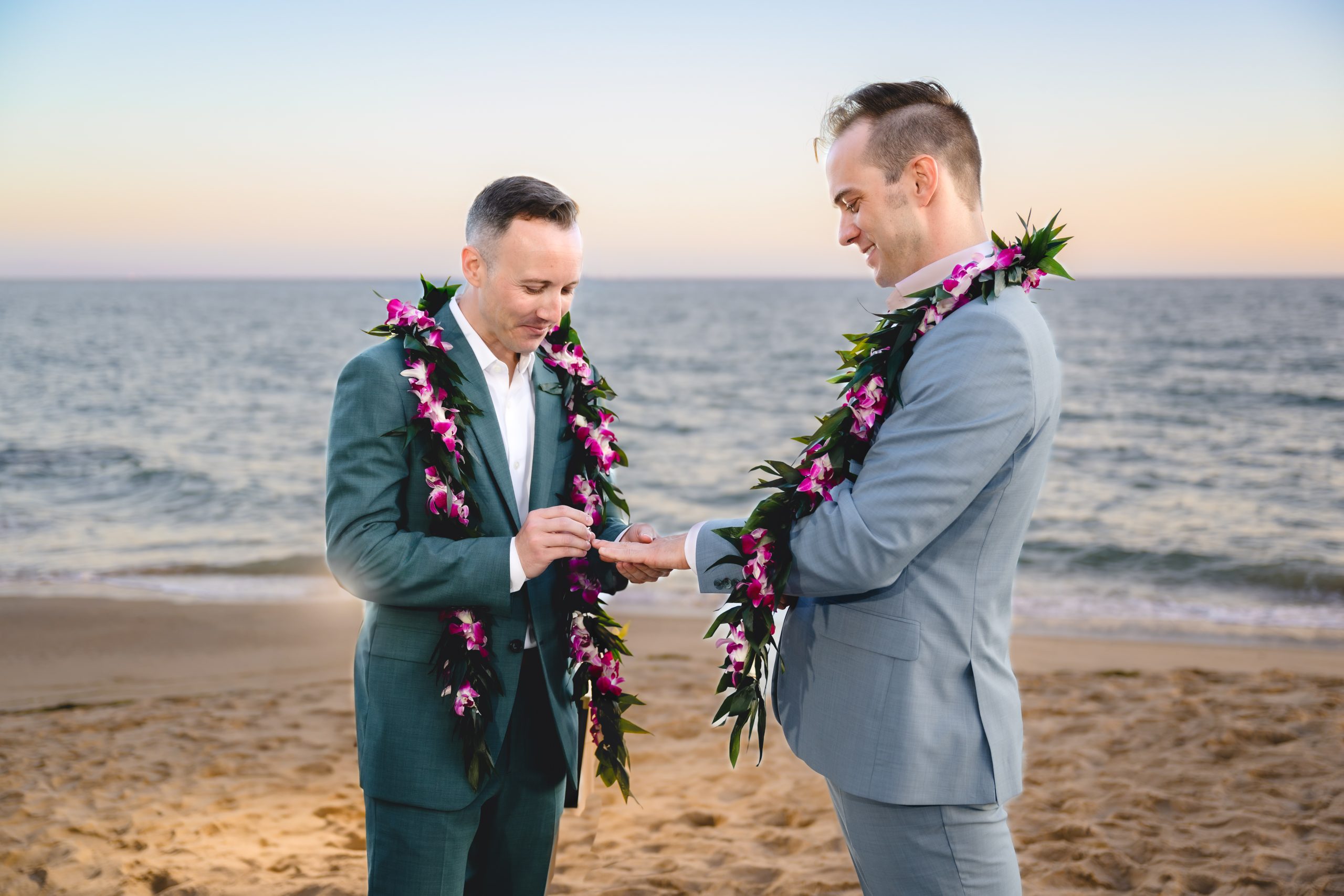 two grooms exchange rings as the sun sets over the ocean in malibu