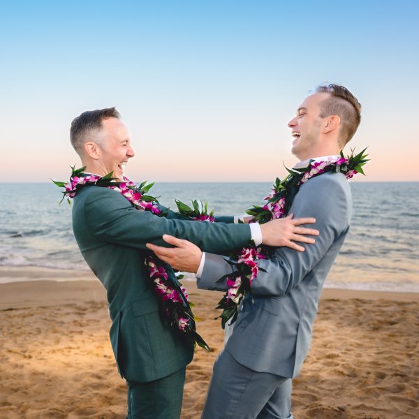 The couple holds each other at arms length as they laugh and look at each other lovingly.