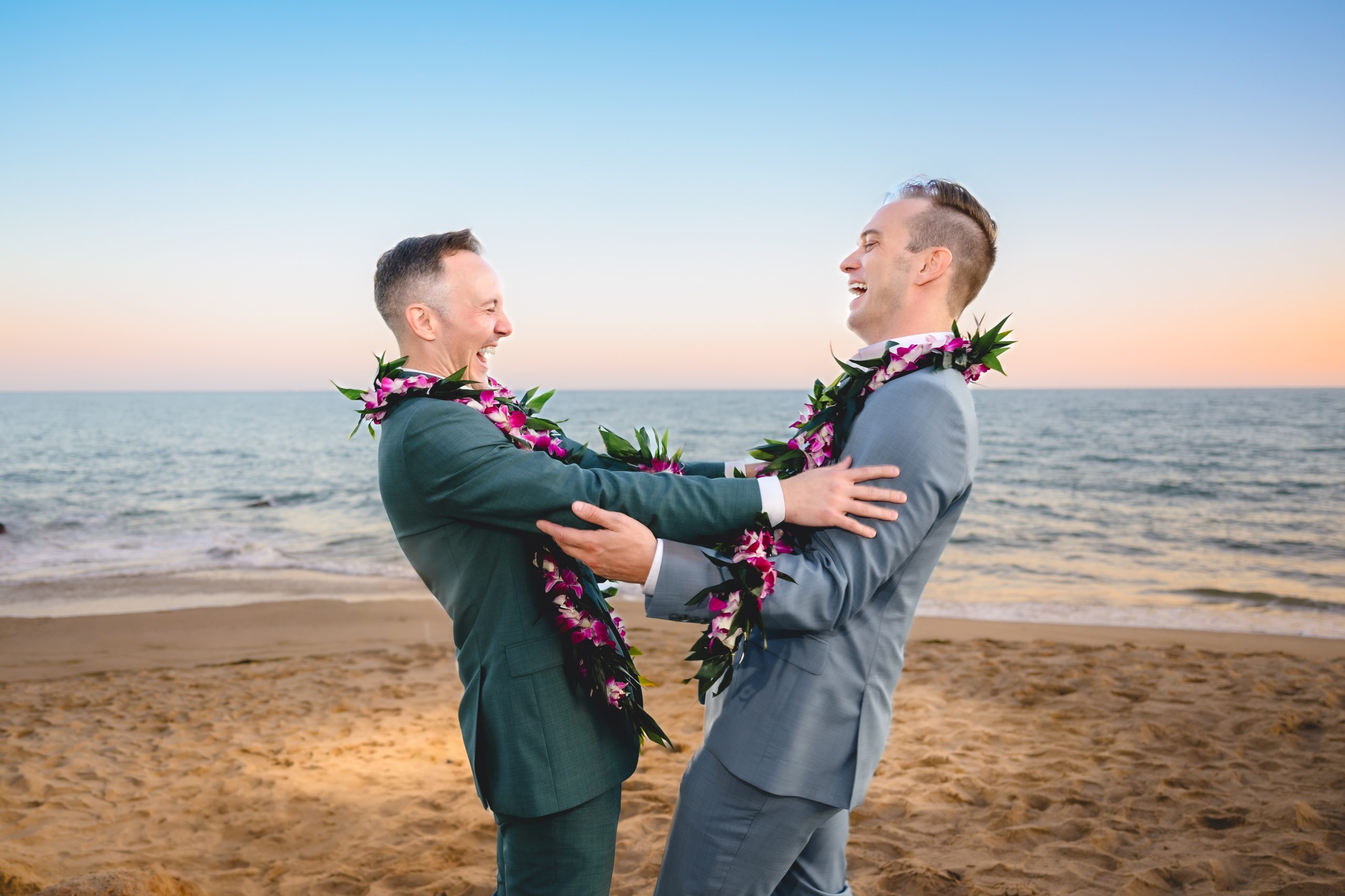 The couple holds each other at arms length as they laugh and look at each other lovingly.