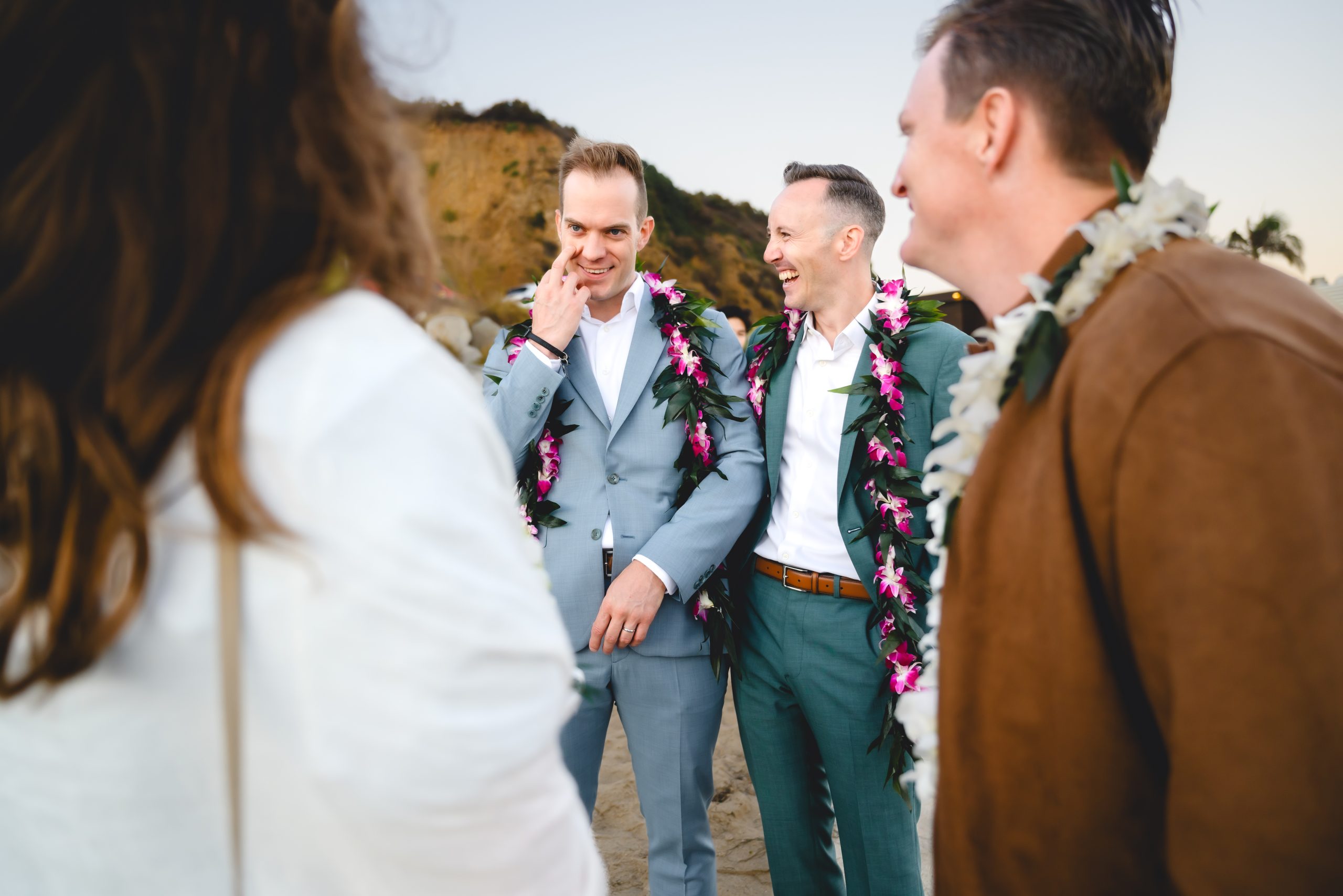the husbands share a joke as they laugh with their wedding guests