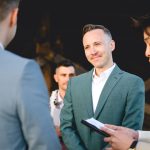 a groom in green gazes lovingly at his husband