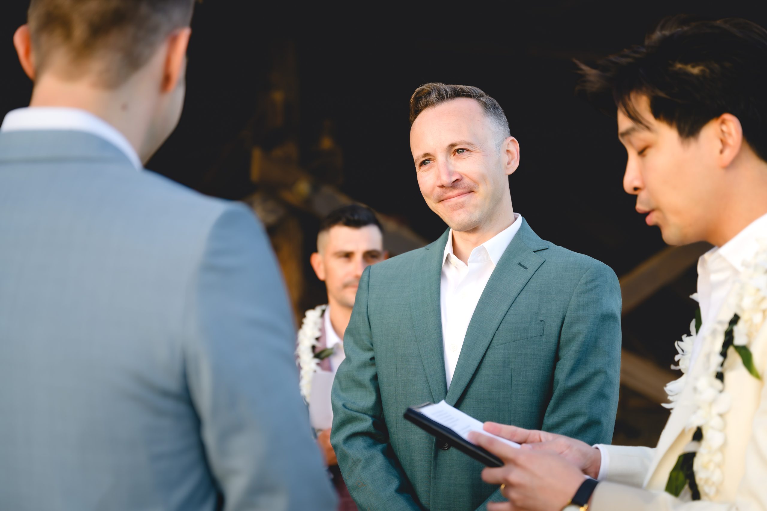 a groom in green gazes lovingly at his husband